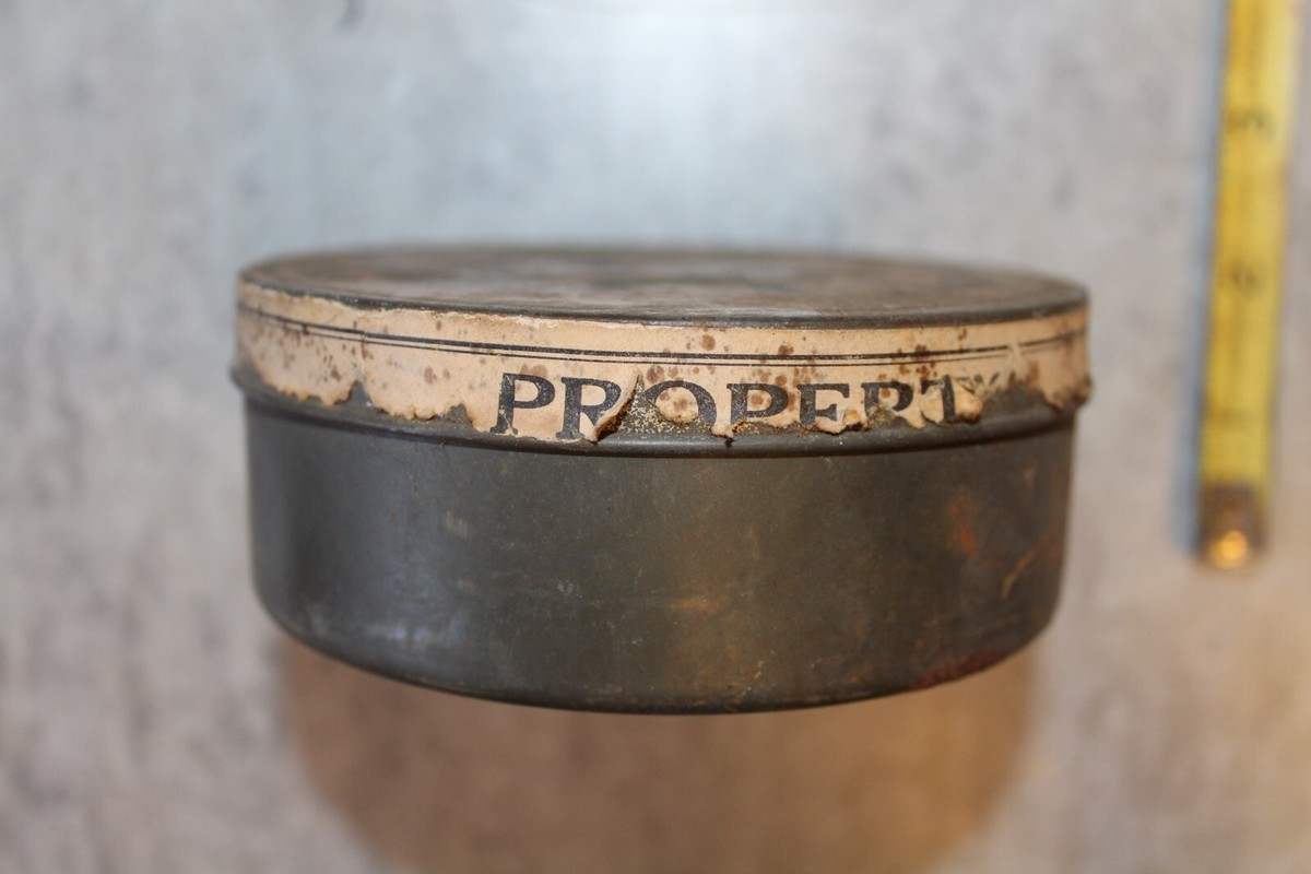 A small open tin of homemade saddle soap style leather cleaner on a warm wood kitchen counter with a soft cloth and a horsehair brush nearby, natural window light