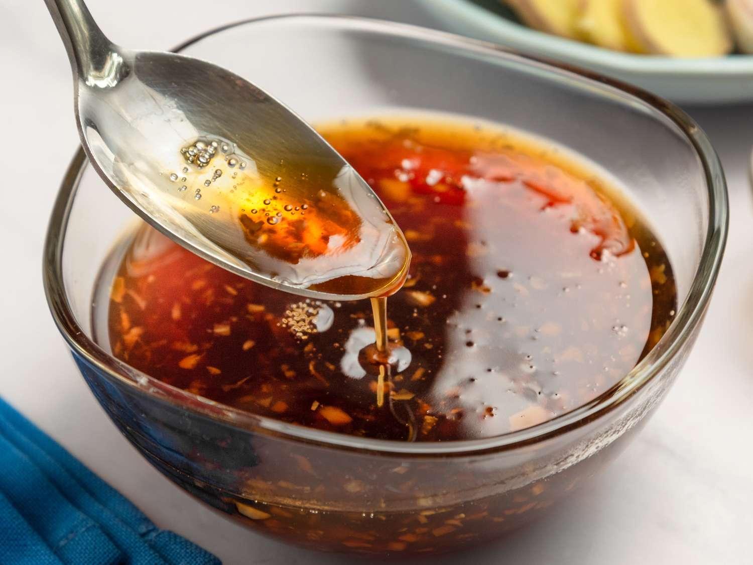 A small saucepan of glossy honey garlic sauce being whisked on a stovetop, warm kitchen lighting