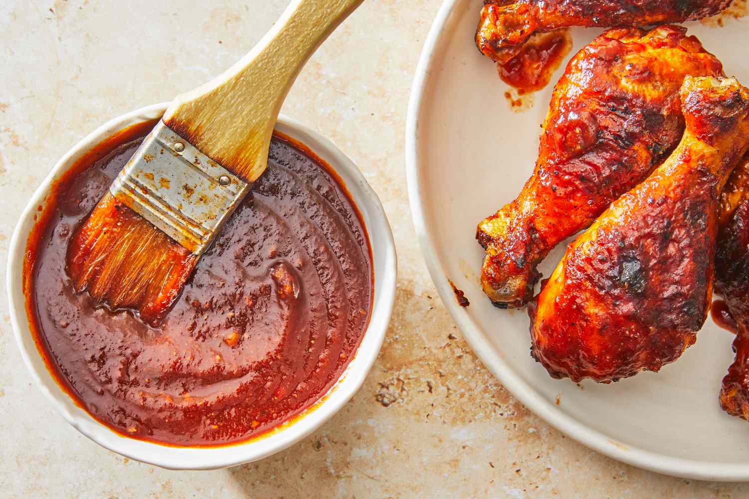 A small saucepan of simmering homemade barbecue sauce on a stovetop with a whisk resting nearby in a cozy kitchen