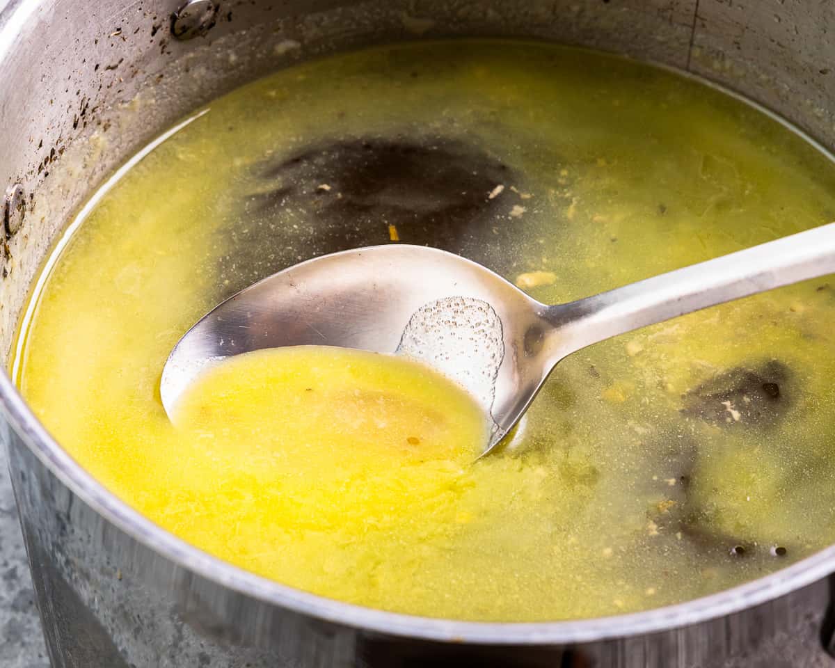 A small saucepan of warm broth on a stovetop with gentle steam rising