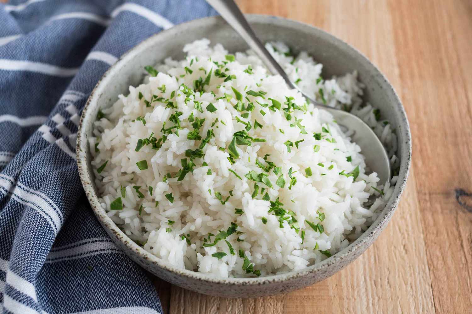 A small saucepan on a stove with white rice simmering under a lid, steam lightly fogging the glass