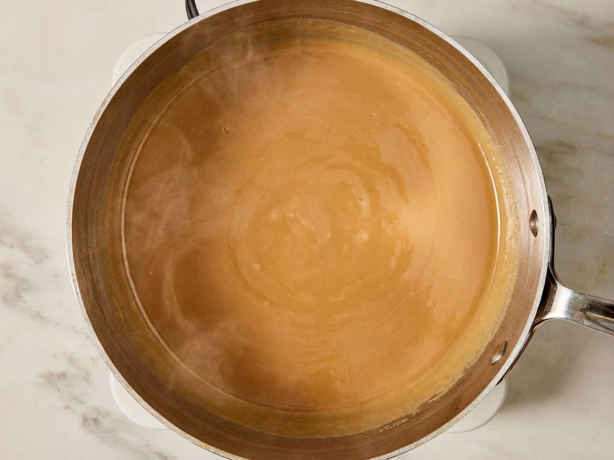 A smooth tan butterscotch cream mixture warming gently in a small saucepan