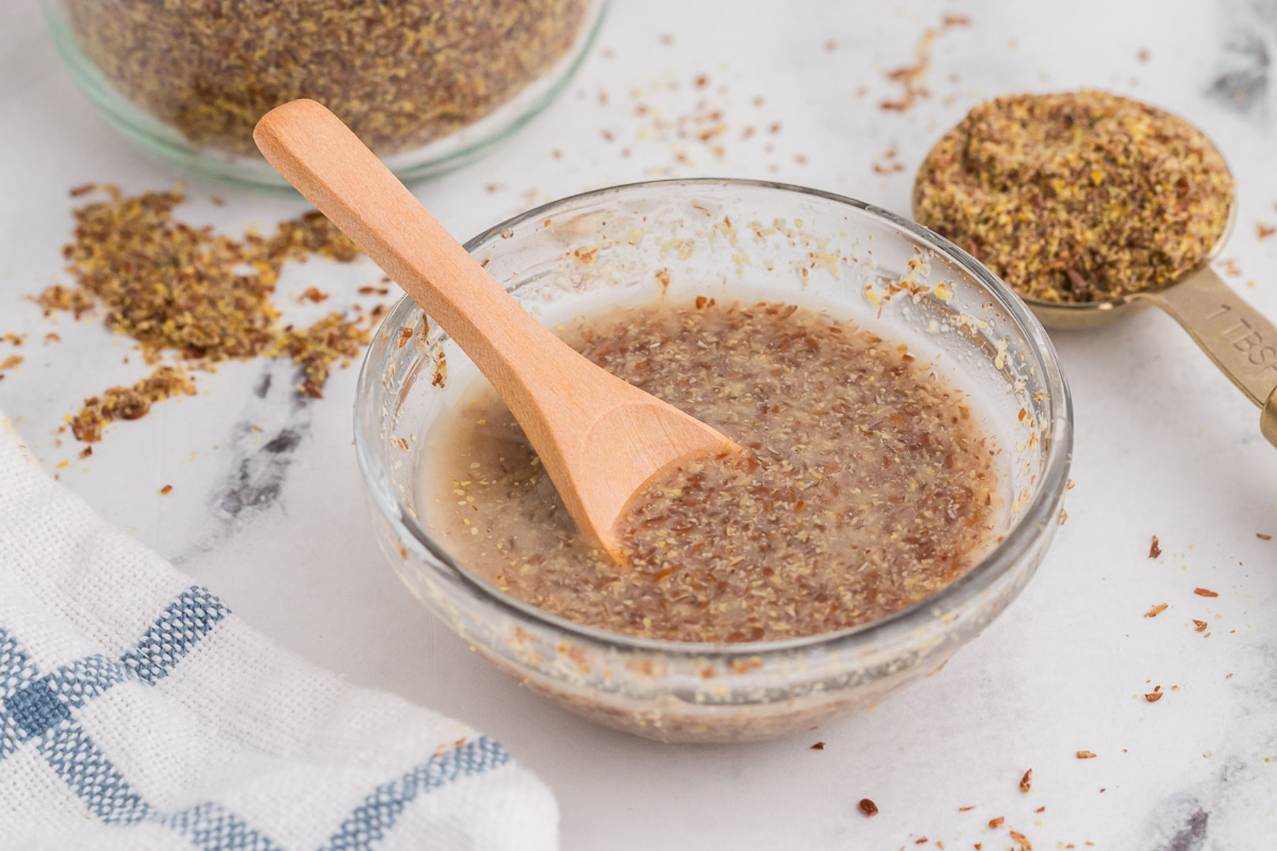 A spoon lifting thickened flax egg gel from a small bowl, showing the glossy, viscous texture