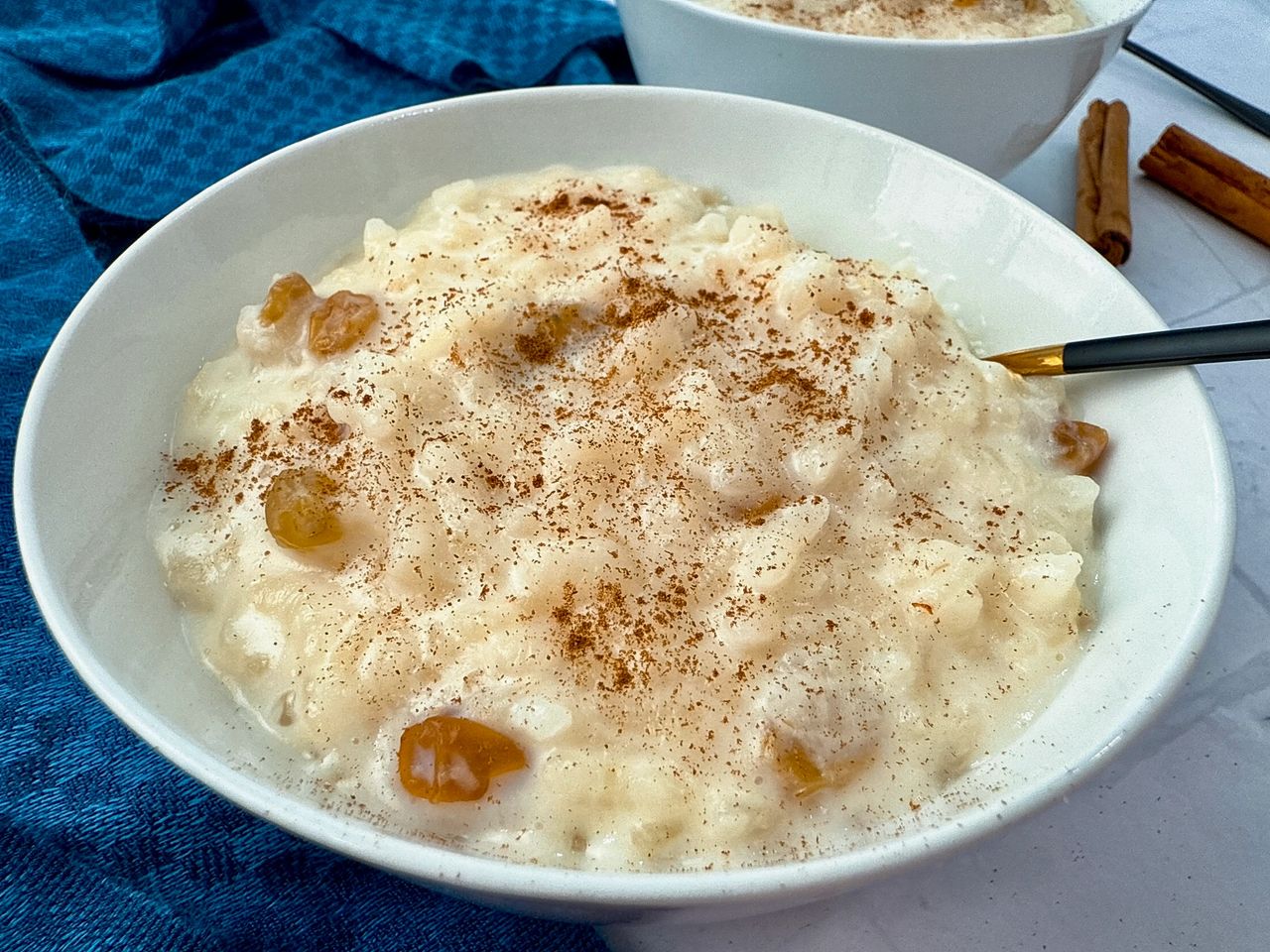 A spoon scooping creamy baked rice pudding from a ceramic dish, showing a custardy texture with tender rice grains