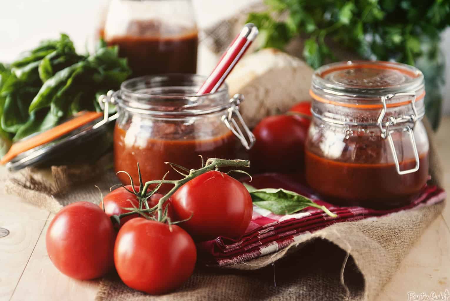 A spoon stirring marinara sauce and crushed tomatoes inside a slow cooker insert on a kitchen counter