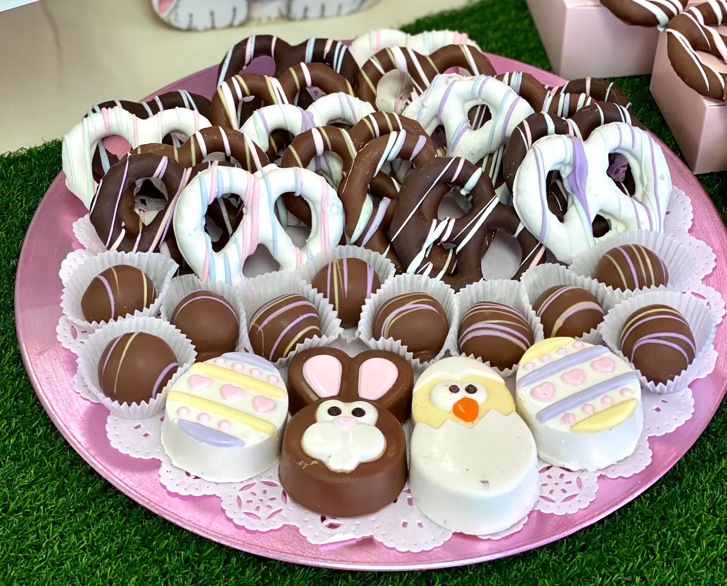 A spring Easter table setting with a platter of chocolate nest cookies and pastel candy eggs, plates and napkins nearby