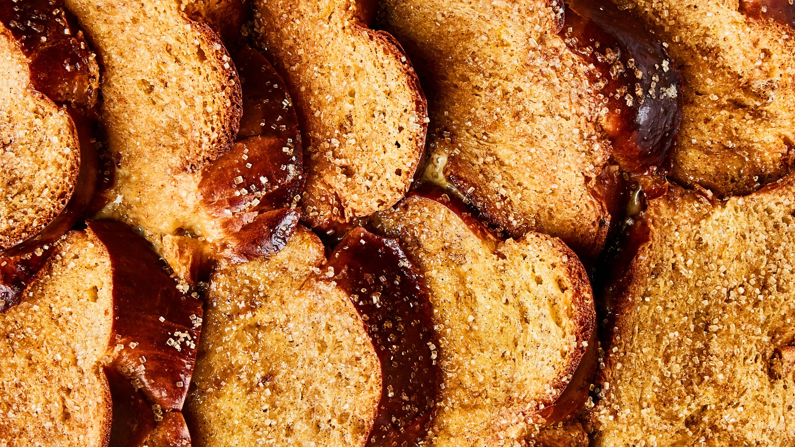 A square slice of French toast bake lifted from the pan showing a custardy interior and browned top, with steam rising