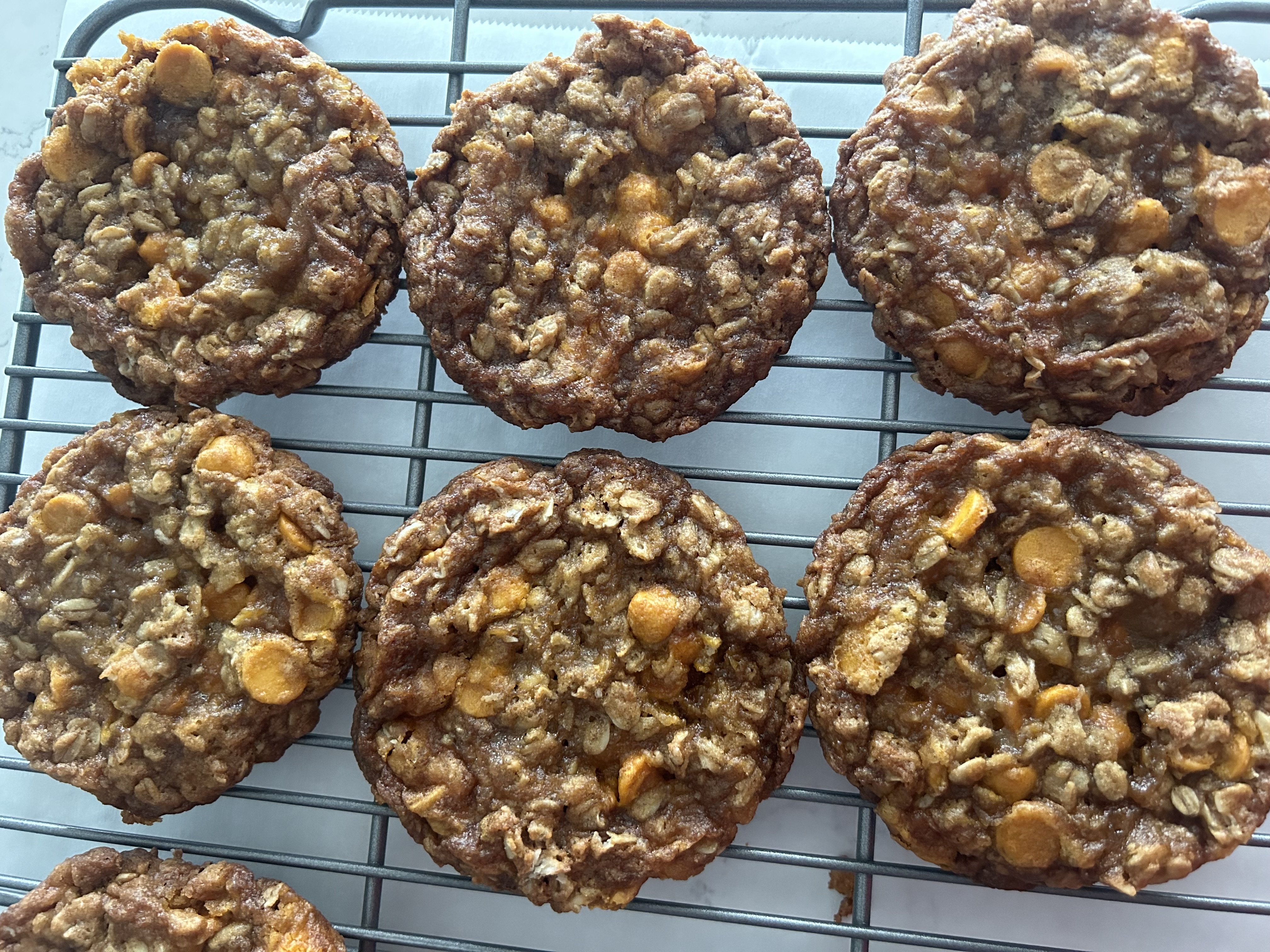 A stack of chewy oatmeal scotchies cookies with visible butterscotch chips on a stoneware plate on a warm kitchen table