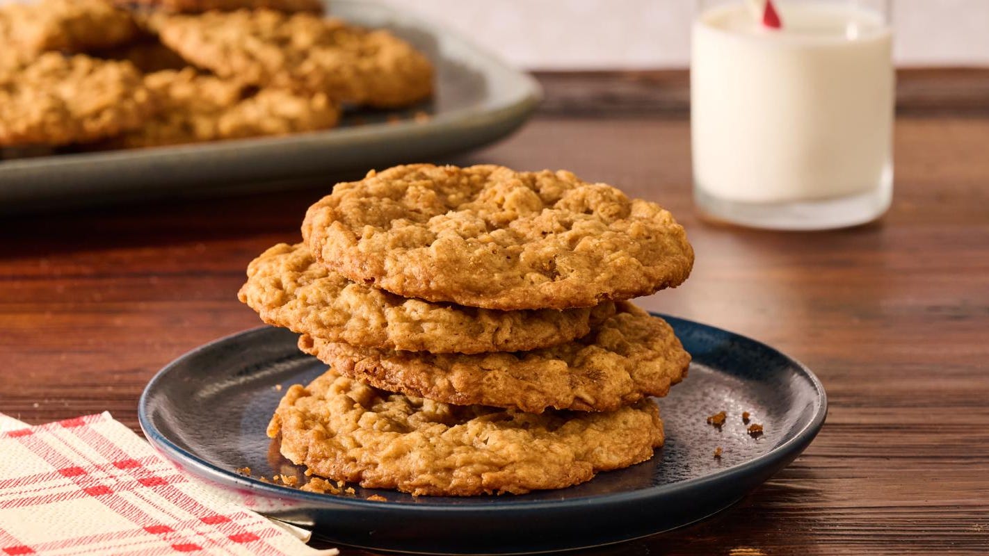 A stack of soft brown sugar cookies with crackly tops on a ceramic plate on a warm kitchen table in natural window light