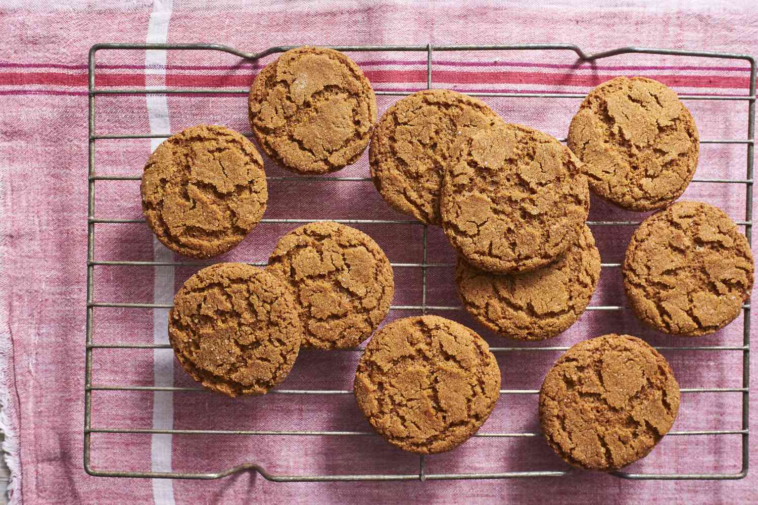 A stack of soft molasses cookies with crackly sugar tops on a stoneware plate on a warm kitchen table, natural window light