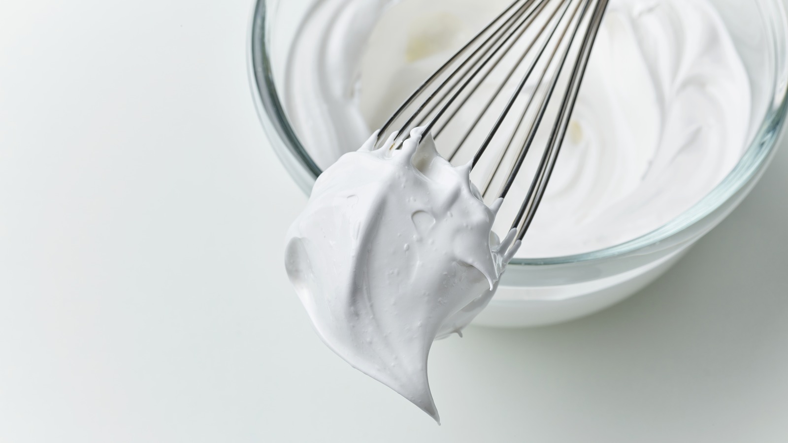 A stainless steel mixing bowl and whisk attachment resting in a freezer drawer, ready for whipping cream