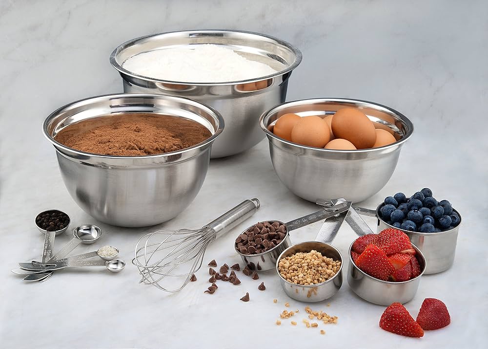 A stainless steel mixing bowl with a whisk and measuring spoons on a bright kitchen counter