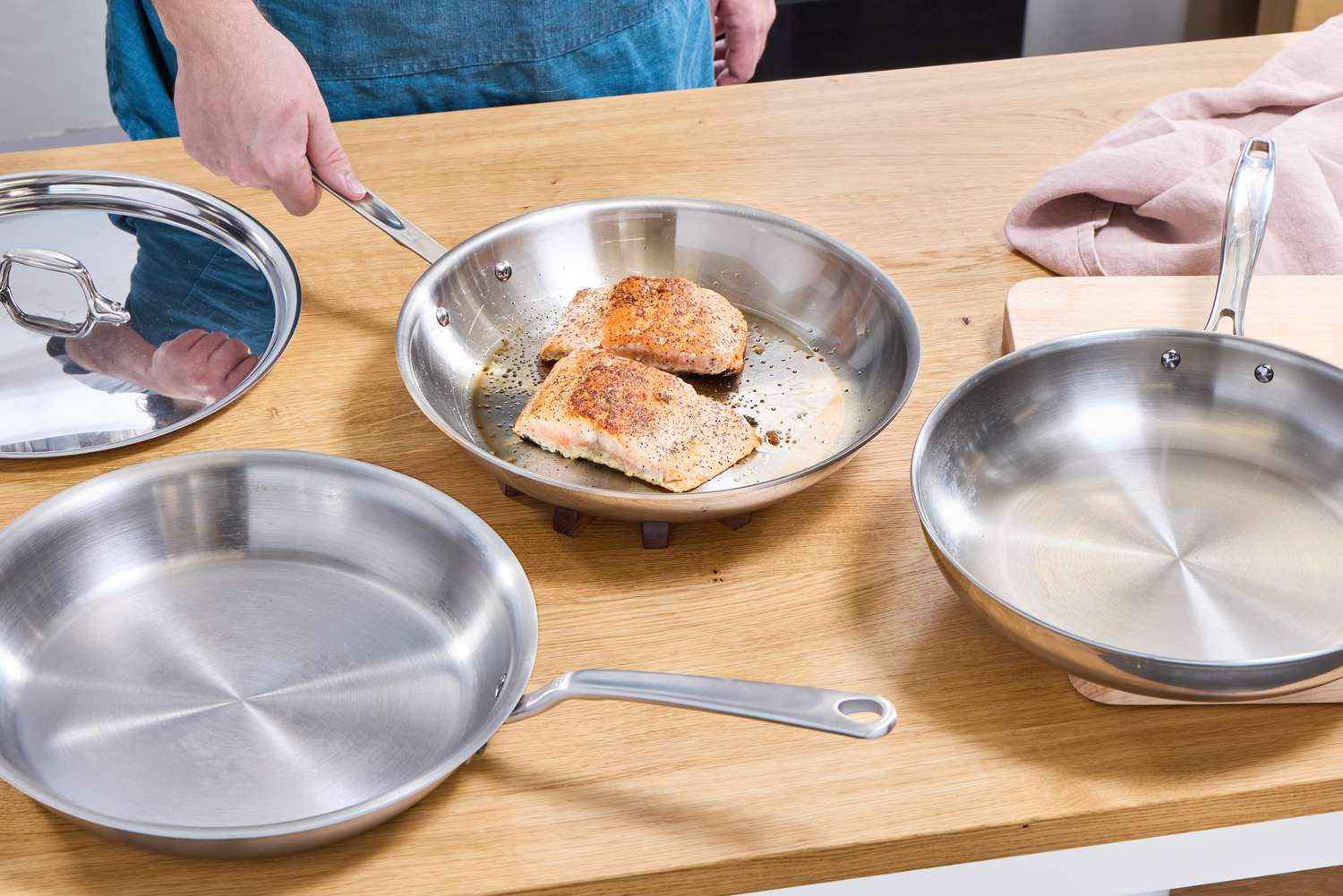 A stainless steel skillet on a stovetop with shimmering oil, ready for searing