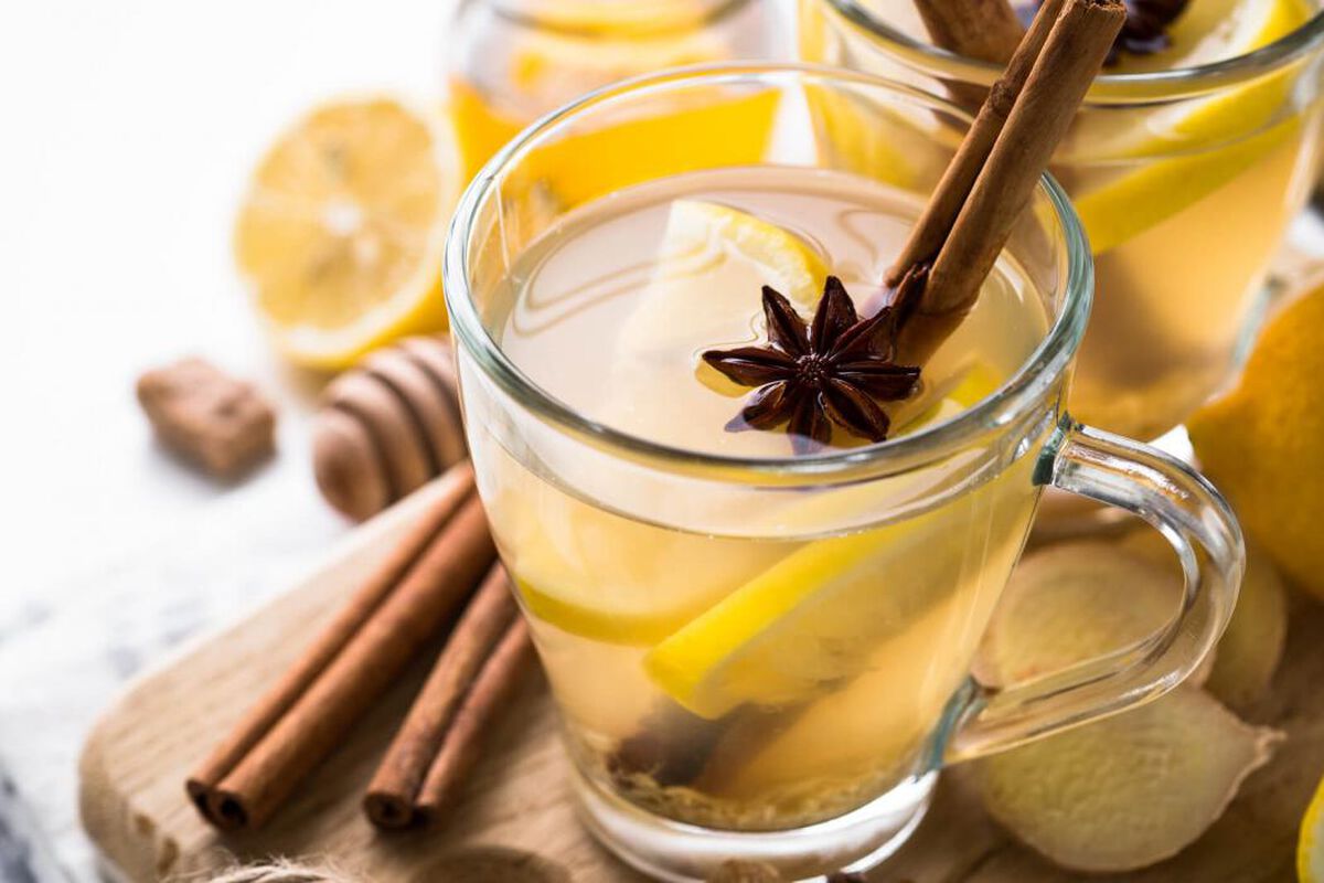 A steaming mug of ginger lemon honey tea on a cozy kitchen counter with sliced lemon and fresh ginger nearby, warm natural light