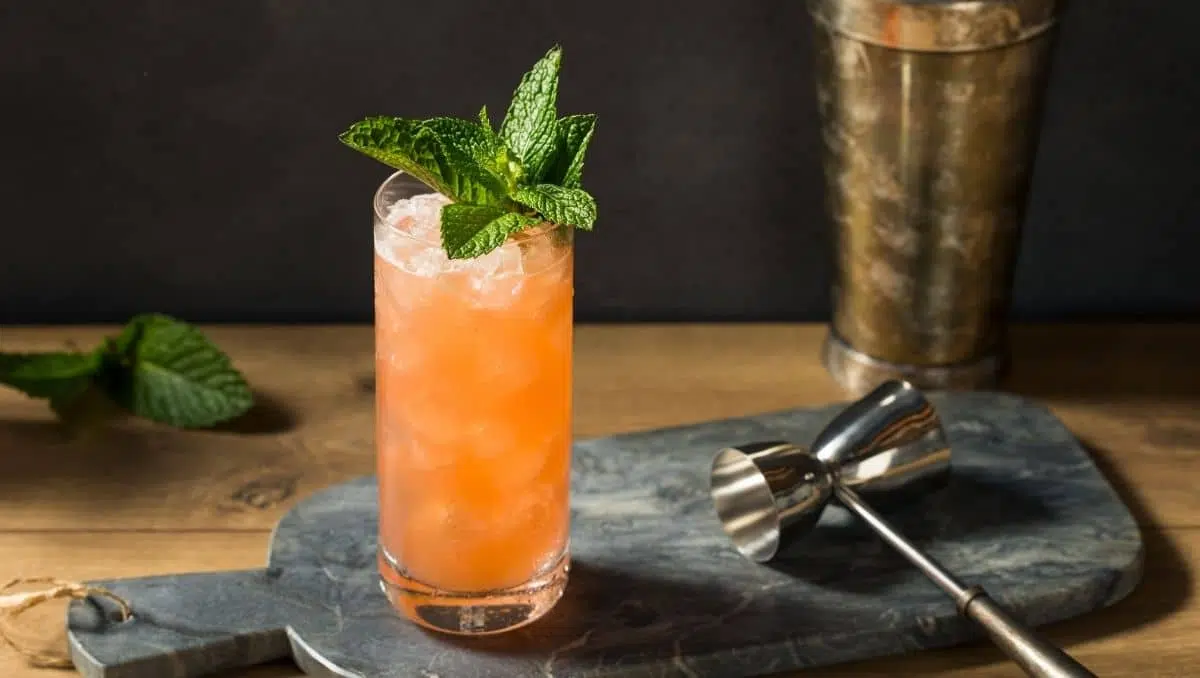 A tall Zombie cocktail in a clear glass packed with crushed ice, garnished with mint and a citrus slice on a warm kitchen counter with soft evening light