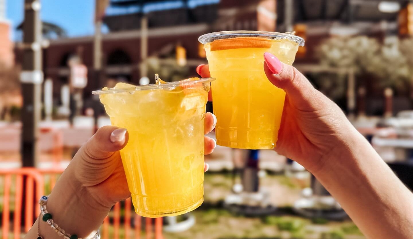 A tall glass of orange crush cocktail with fresh orange juice and lemon-lime soda, filled with crushed ice and garnished with an orange slice on a bright kitchen counter