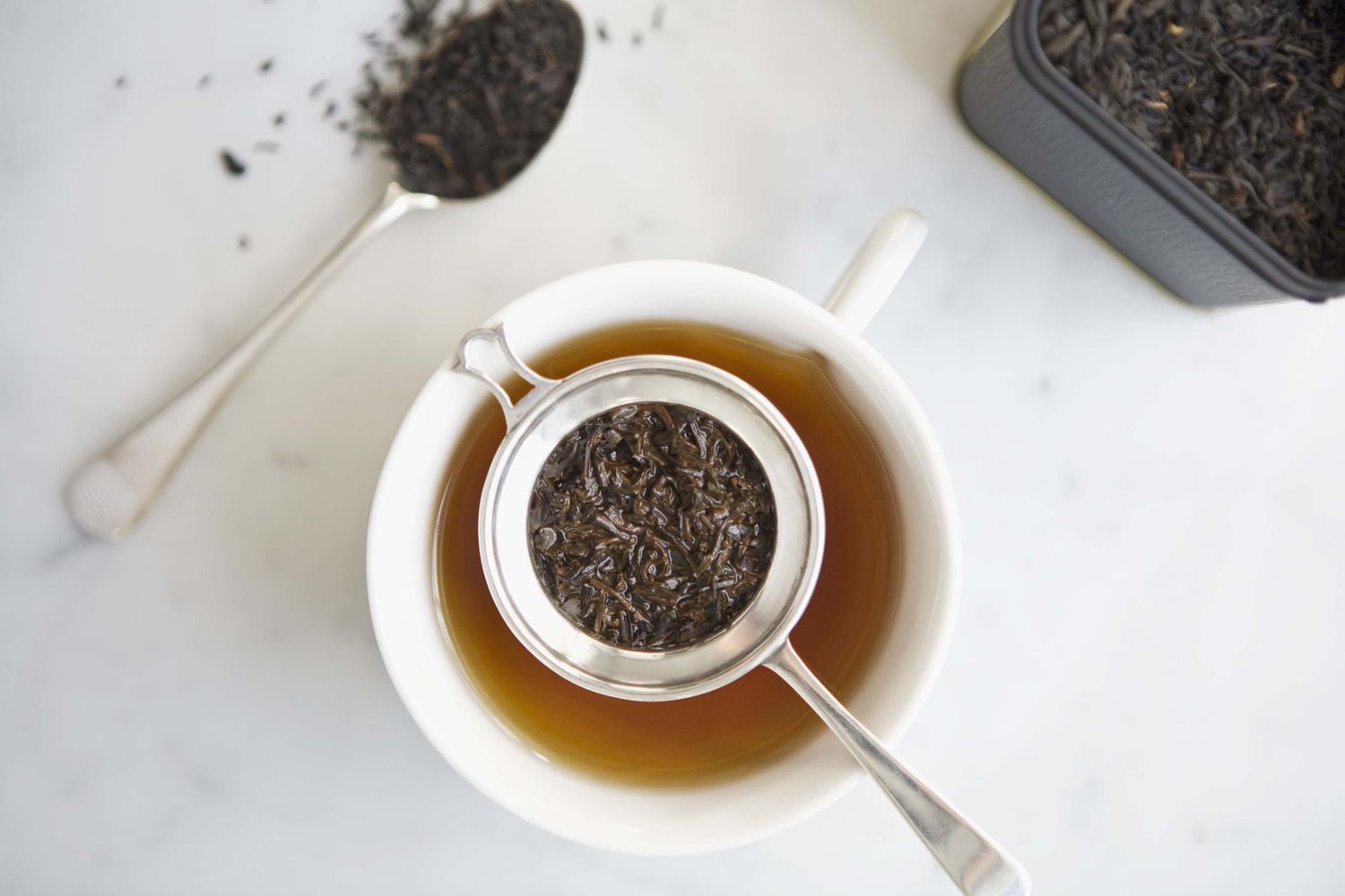 A tea bag steeping in a clear glass mug with amber-colored Earl Grey tea on a kitchen counter