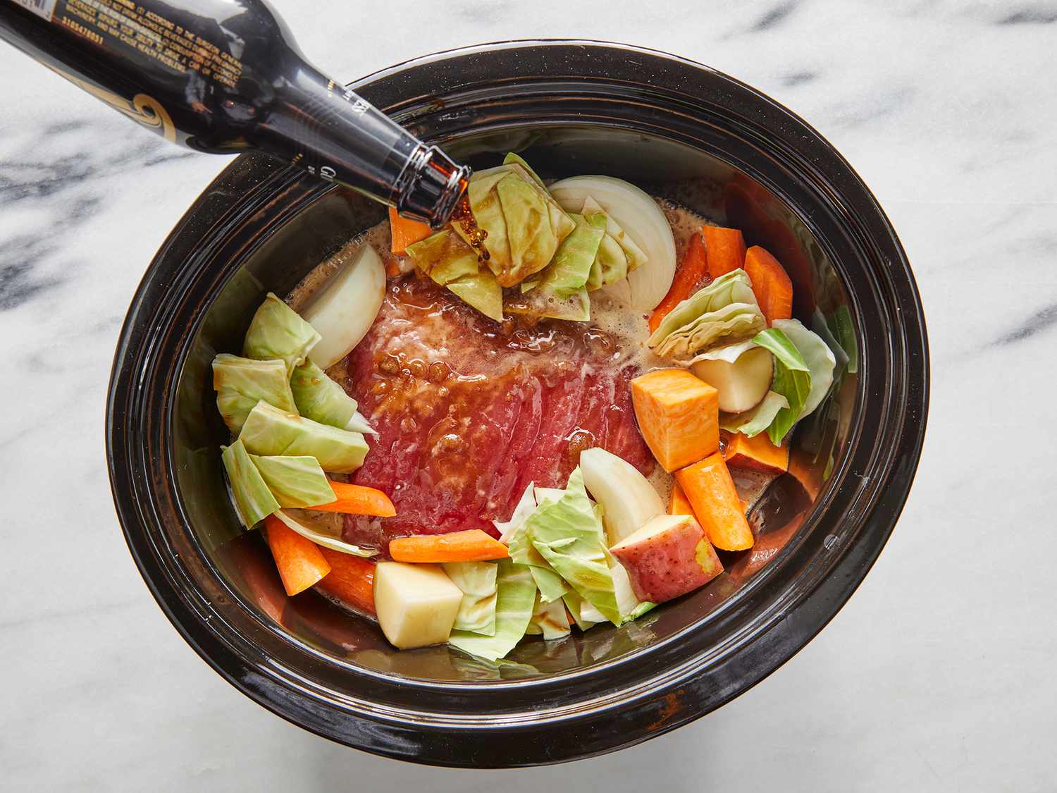 A tender corned beef brisket cooking in a slow cooker with potatoes and carrots, with steam rising when the lid is lifted