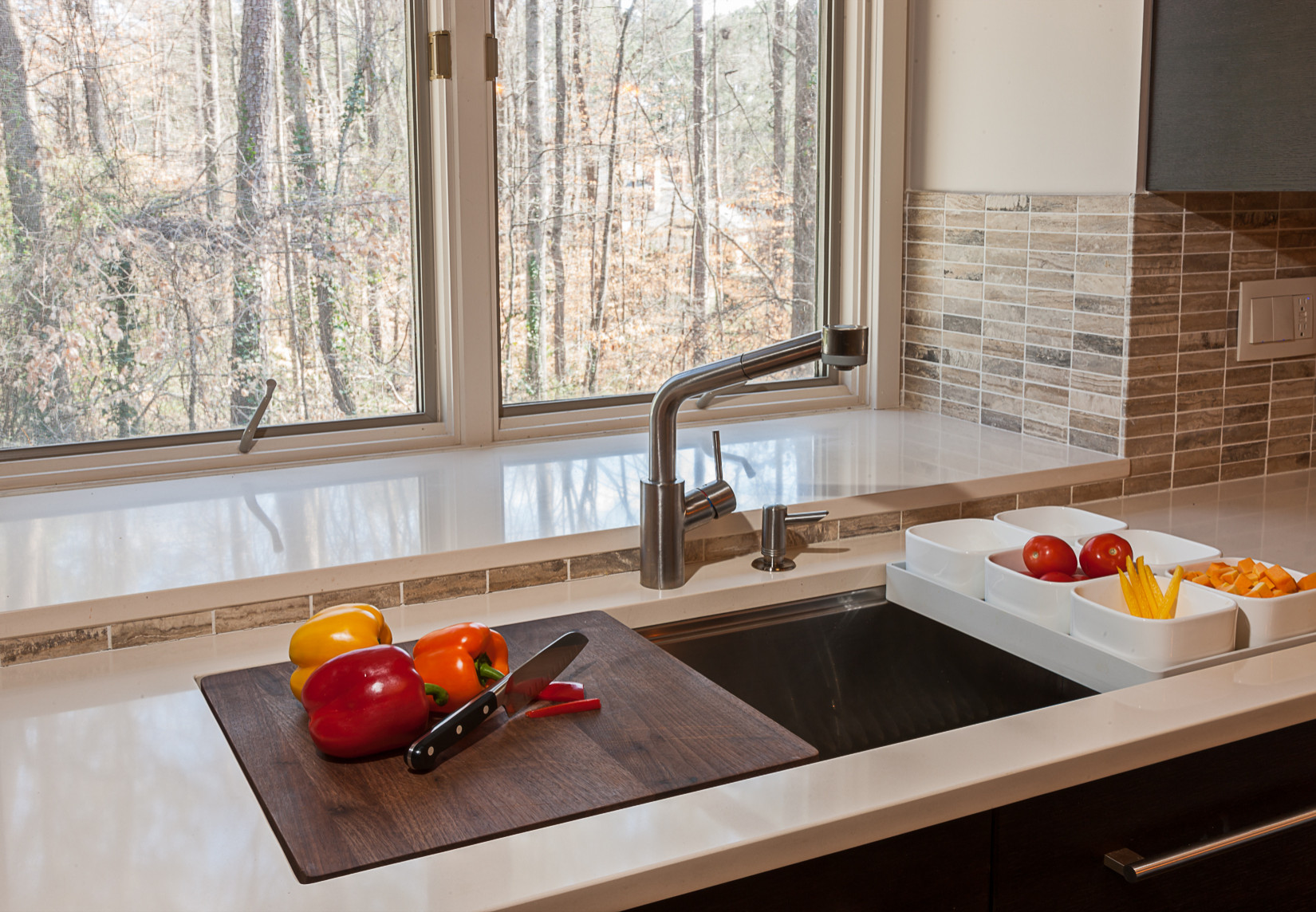 A tidy kitchen counter with small glass prep bowls lined up and a cutting board in the center