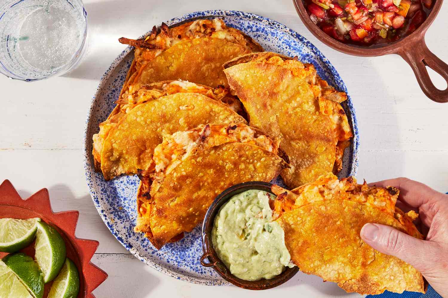 A tray of crispy sheet-pan tacos filled with shredded rotisserie chicken and melted cheese, topped with quick pickled onions and cilantro on a warm kitchen counter