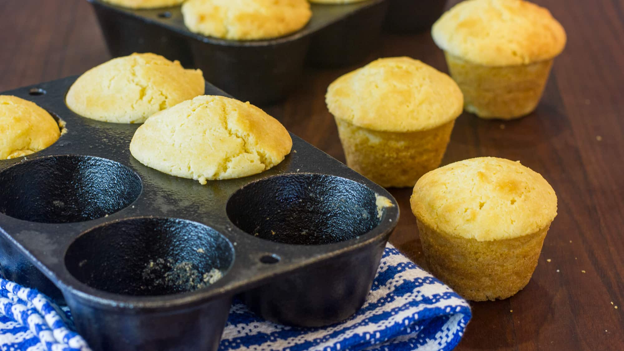 A warm cast iron skillet filled with golden corn muffins, lightly browned tops, on a cozy kitchen counter with a linen towel nearby