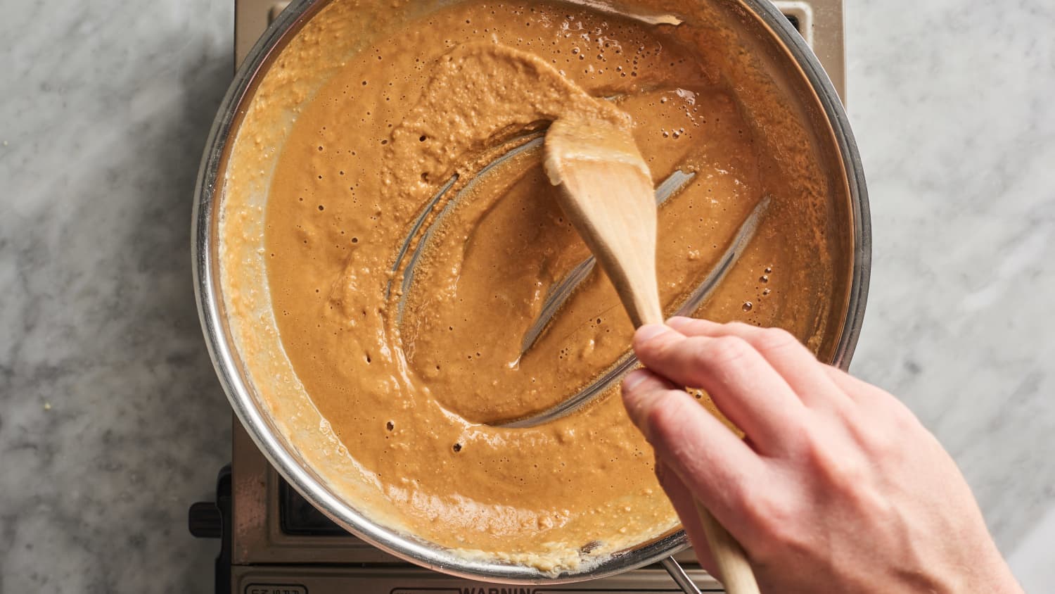 A whisk stirring melted butter and flour into a smooth roux in a saucepan on the stove
