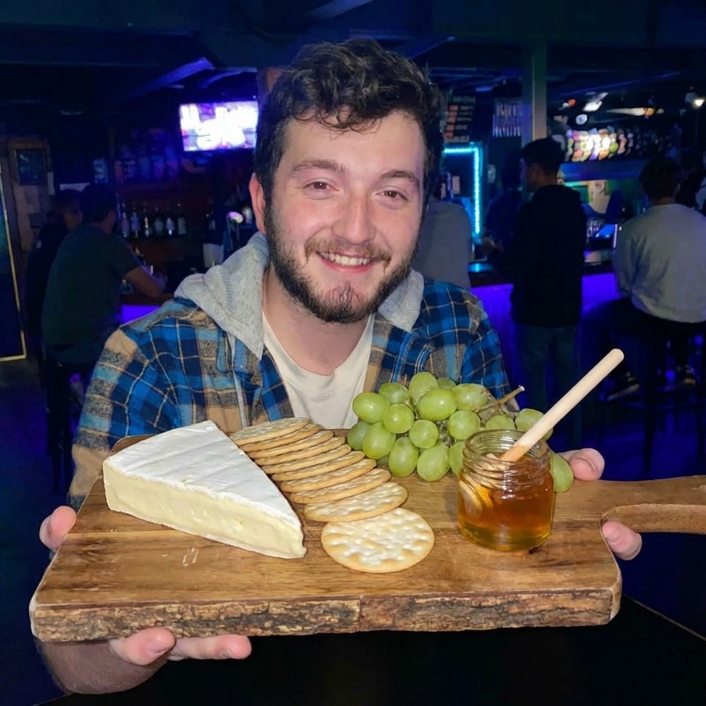 A wooden board with brie, crackers, green grapes, and honey