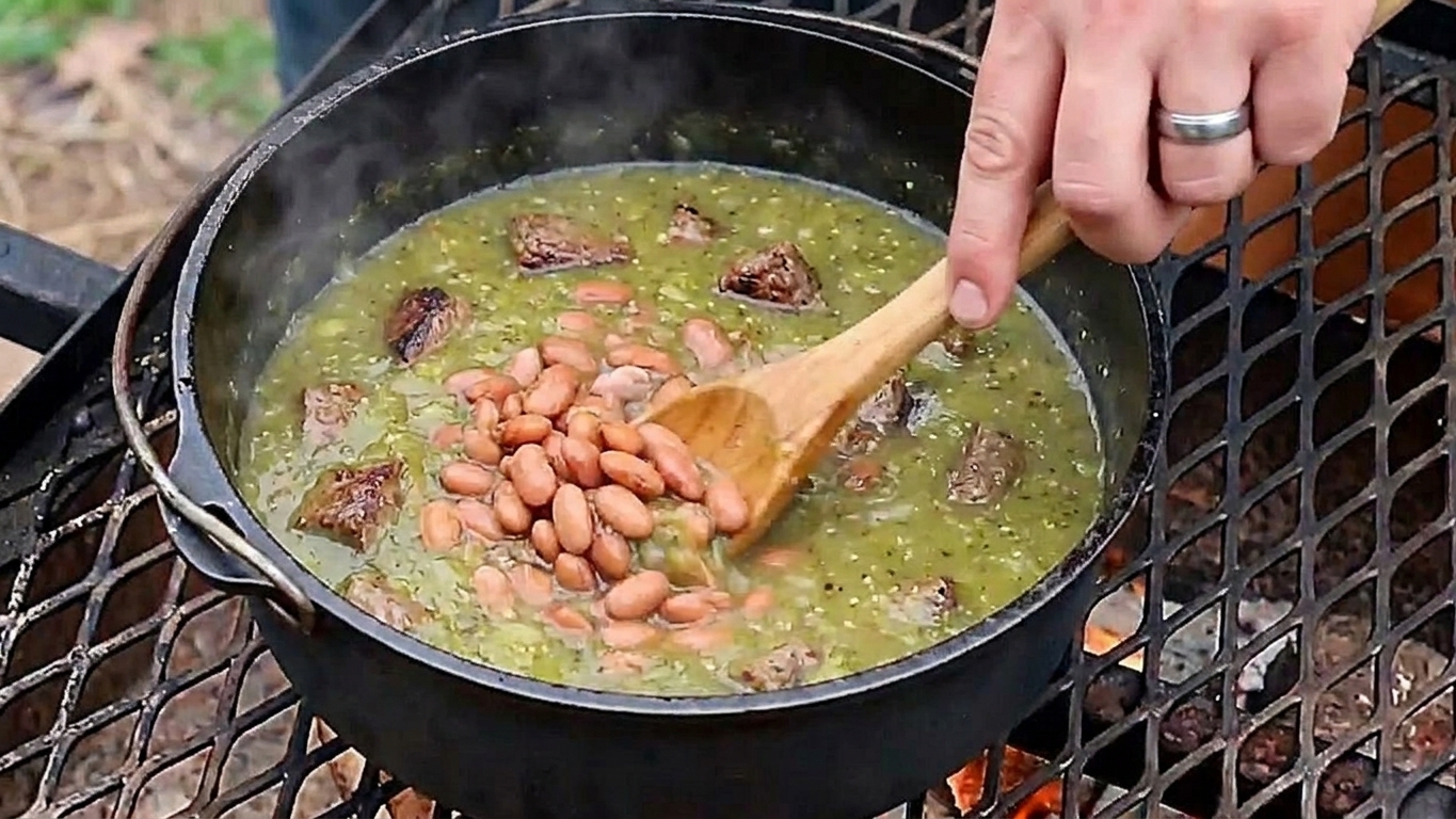 A wooden spoon stirring pinto beans into a simmering green tomatillo beef stew in a pot