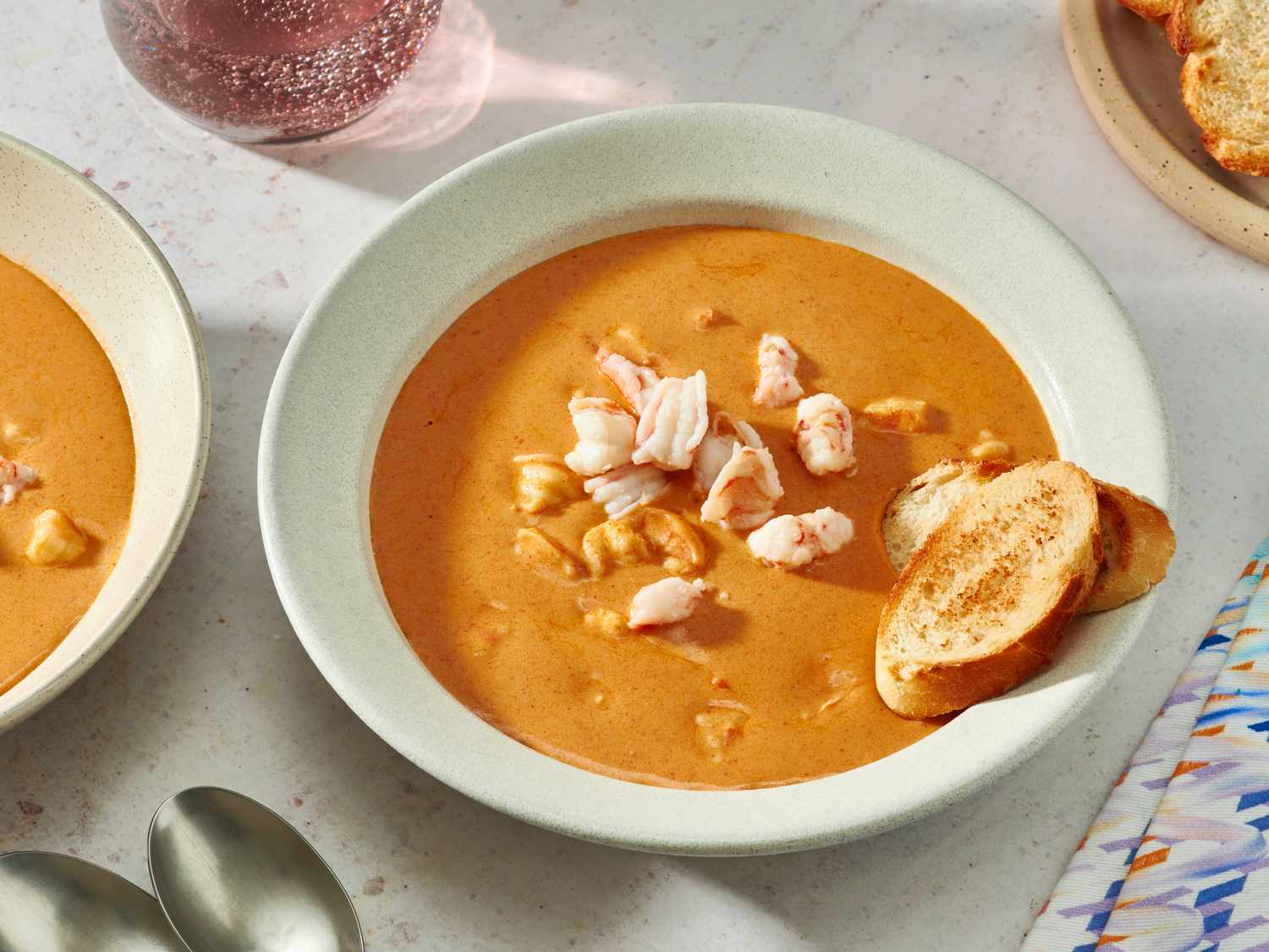 All seafood bisque ingredients arranged on a kitchen counter including shrimp, crab, onion, celery, carrot, cream, and seasonings