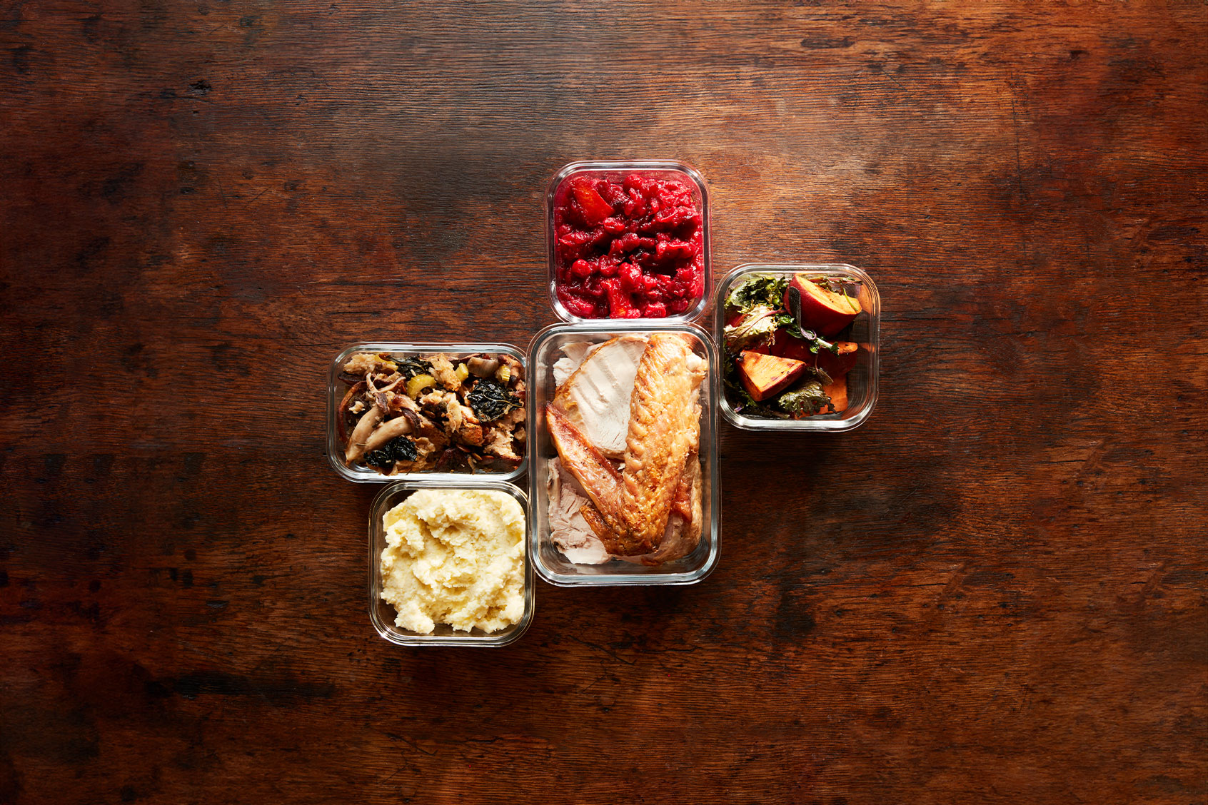 An airtight glass container filled with leftover bread dressing on a kitchen counter with the lid set beside it