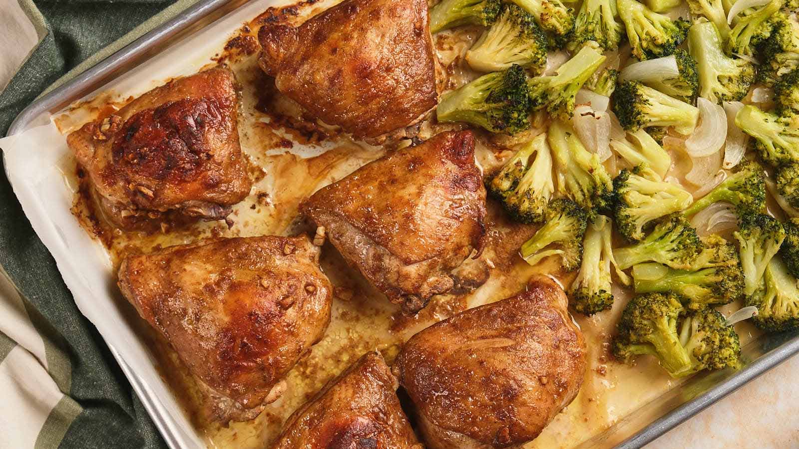 Baked chicken thighs resting on a sheet pan with crispy skin and browned edges
