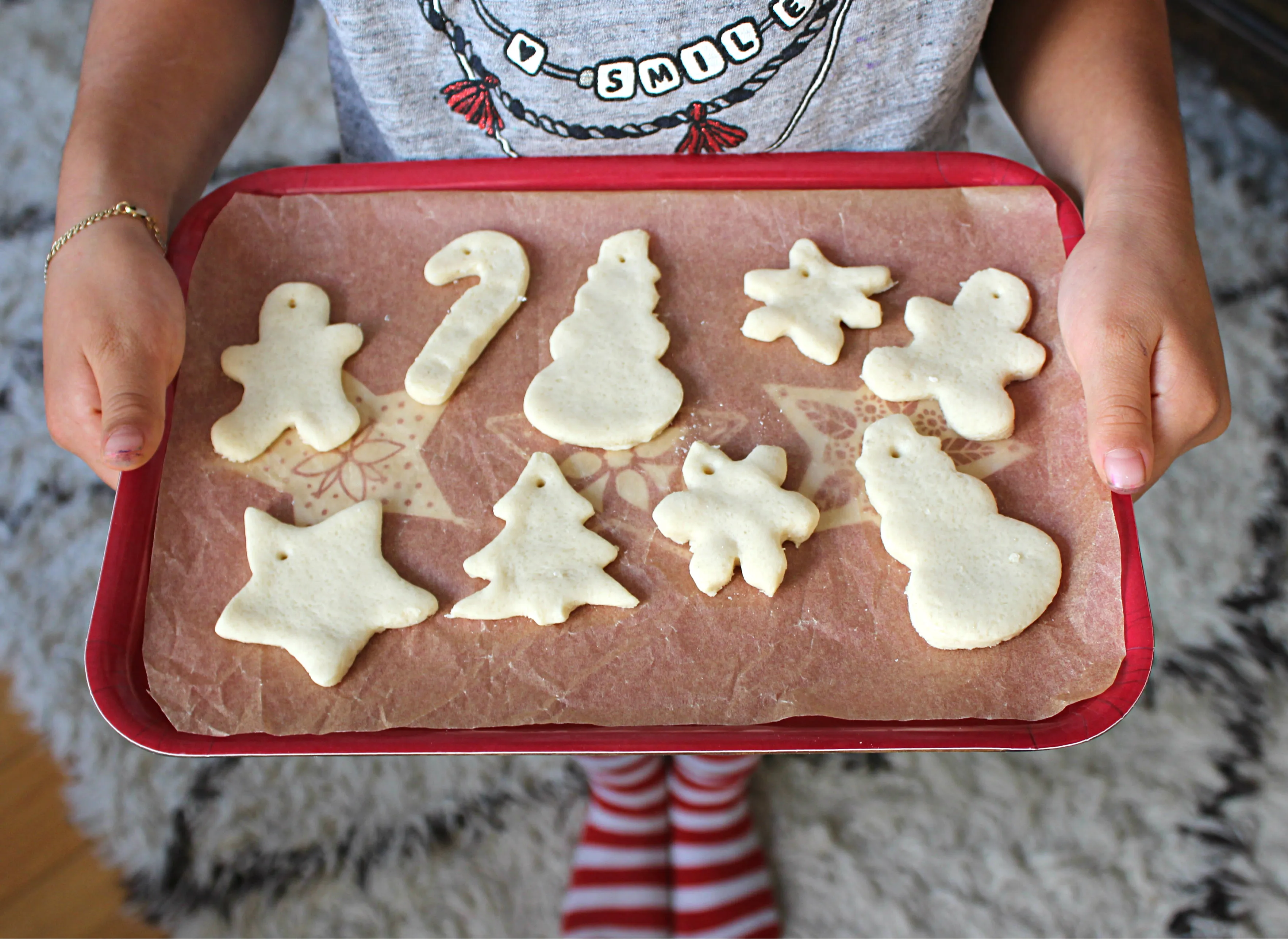 Baked salt dough ornaments cooling on a parchment-lined baking sheet on a light wood kitchen counter with soft window light
