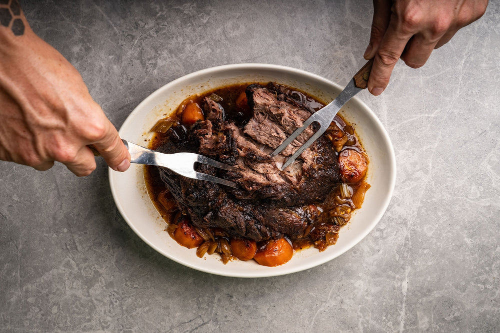 Beef chunks gently simmering in broth with onions and bay leaves, steam rising as the liquid bubbles softly