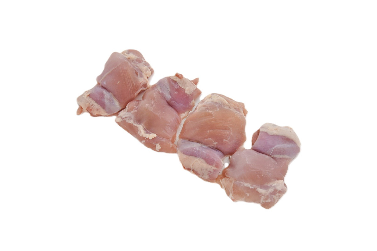 Bowl of bite-size raw chicken thigh pieces seasoned with salt and pepper on a kitchen counter