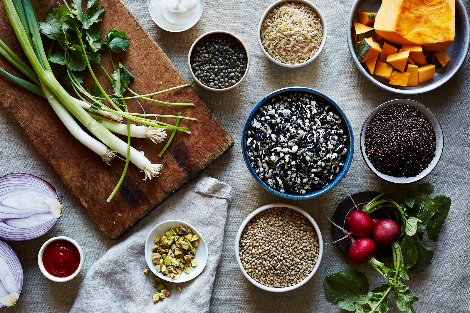 Bowls of chopped vegetables, canned chickpeas, cooked rice, lemon, garlic, and yogurt arranged on a tidy kitchen counter with warm natural light