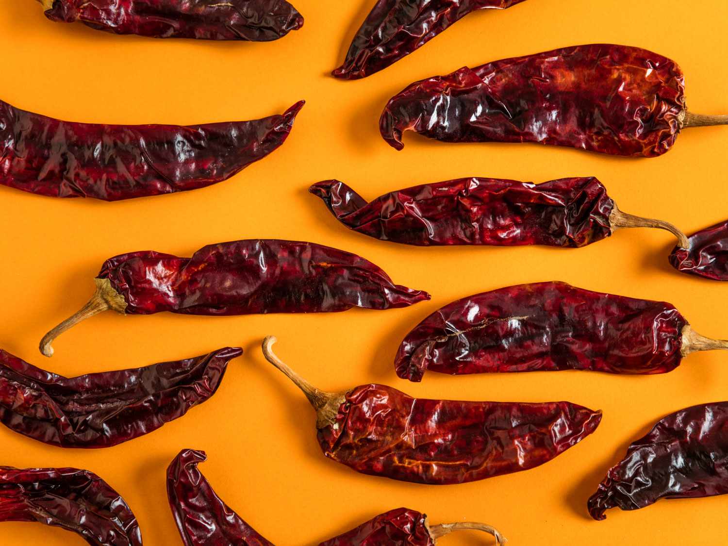 Bowls of dried chiles, garlic cloves, vinegar, spices, and tomato paste arranged on a kitchen counter ready for cooking
