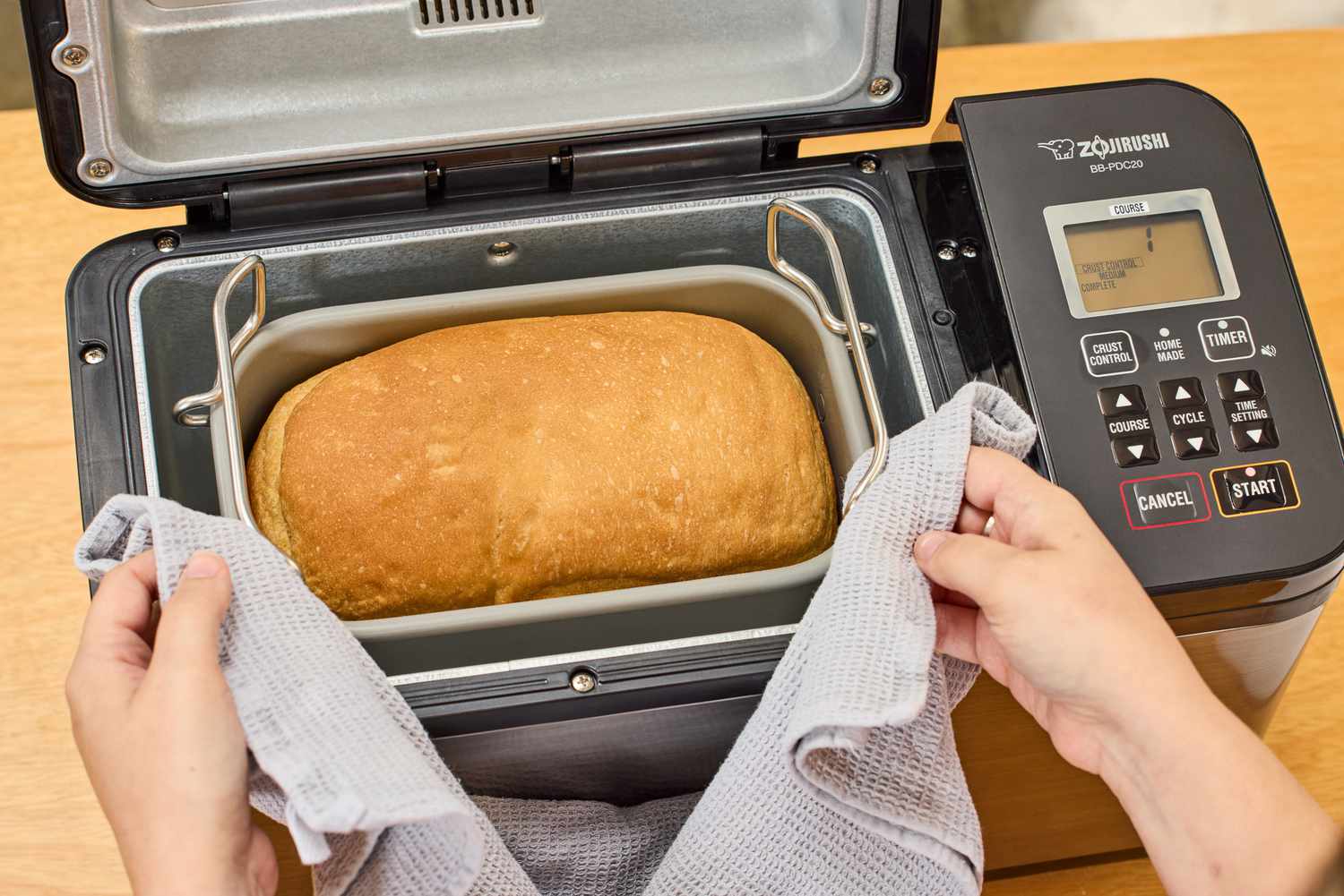 Bread machine pan with liquids and flour added, with a small well in the flour holding yeast before mixing
