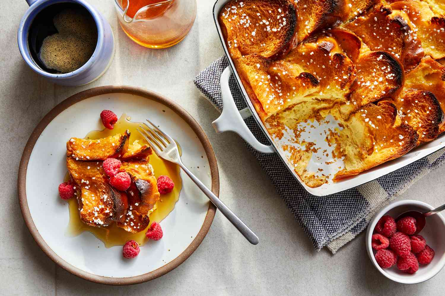 Brioche cubes, eggs, milk, vanilla, cinnamon, brown sugar, butter, and salt arranged on a clean kitchen counter in soft morning light