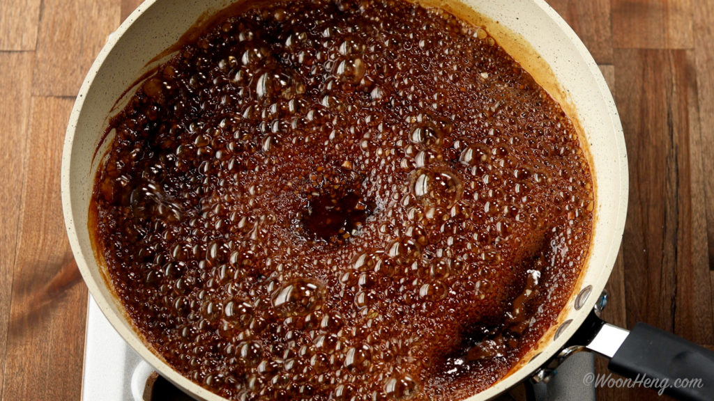Brown sugar melting into hot coffee in a small saucepan on a stovetop with a whisk resting nearby