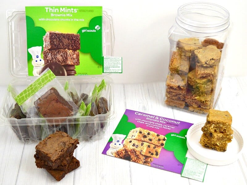 Brownie squares stacked in an airtight glass container with parchment between layers