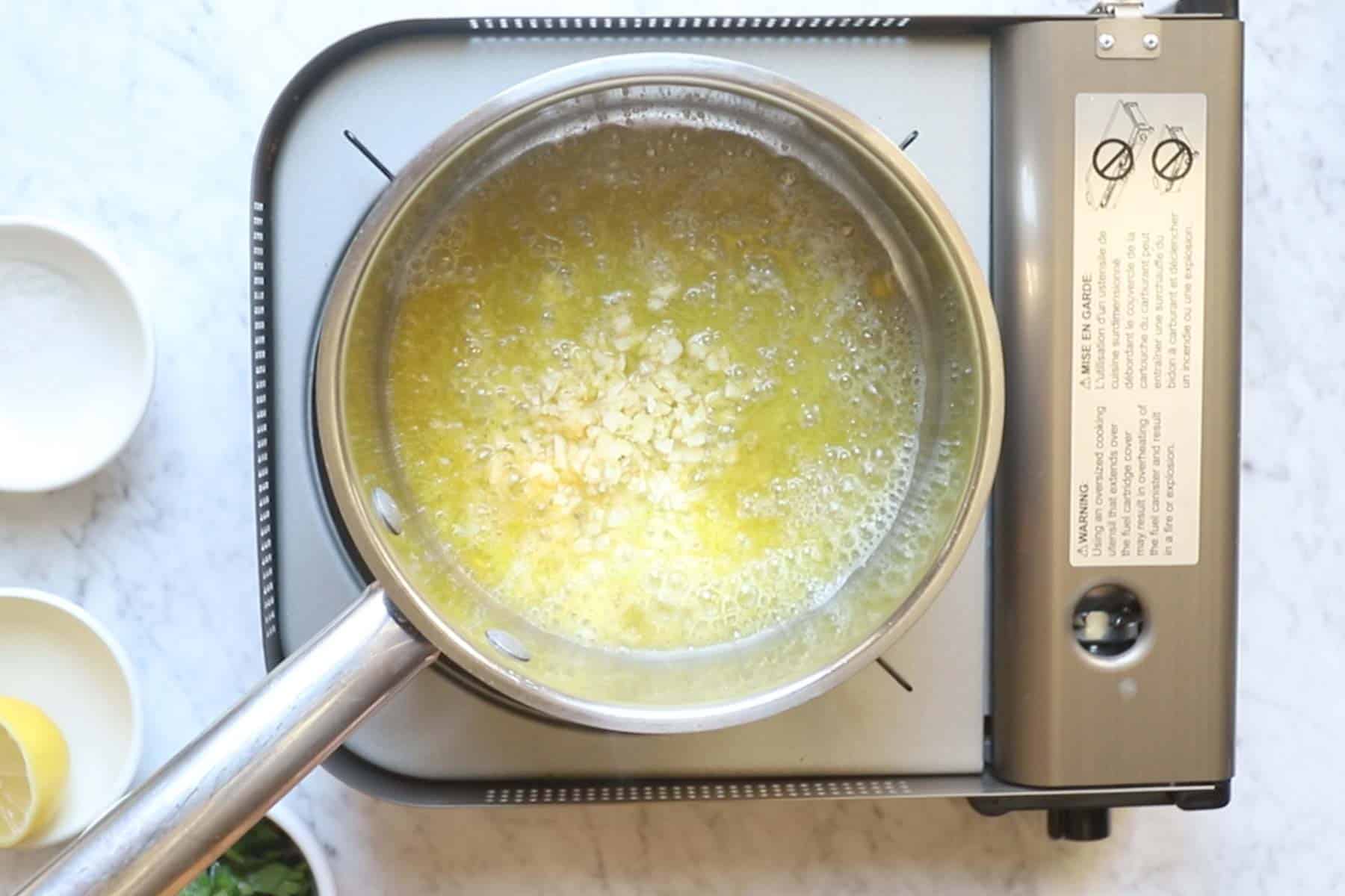 Butter and minced garlic in a slow cooker insert, ready to melt and cook
