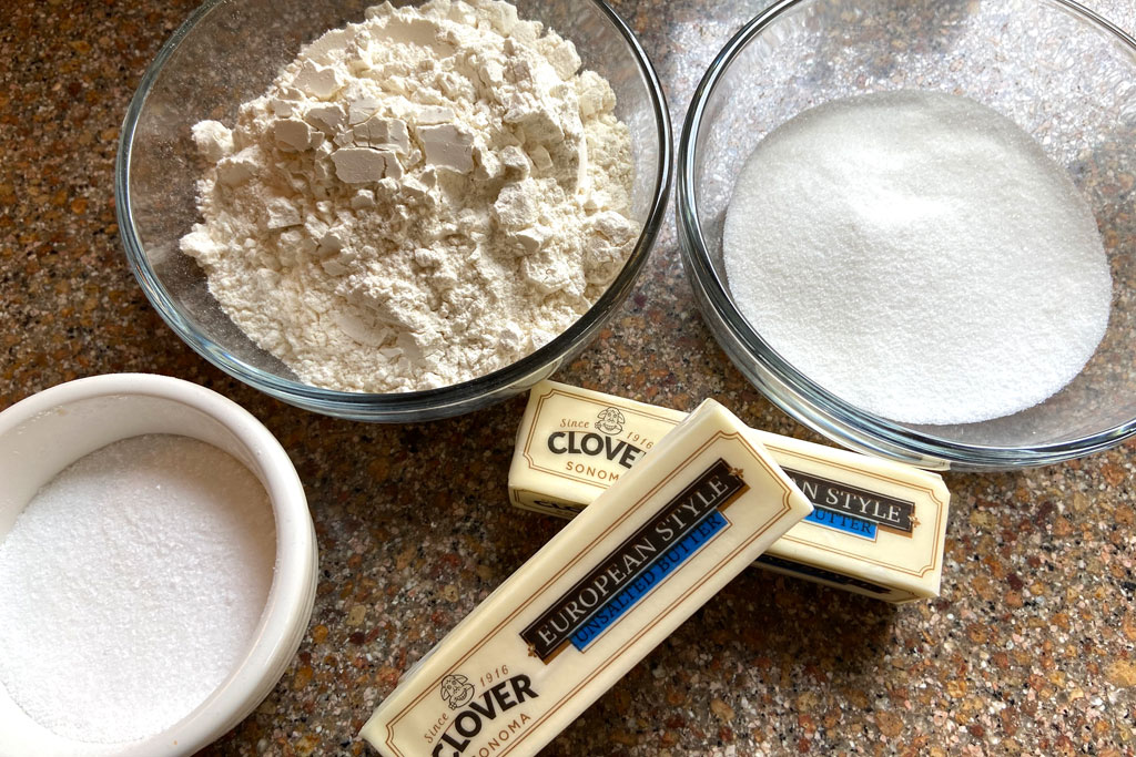 Butter, flour, sugar, salt, and vanilla measured on a clean kitchen counter with a mixing bowl nearby