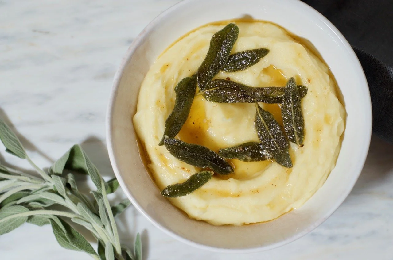 Butter foaming and turning golden brown in a small saucepan while fresh sage leaves fry on a stovetop