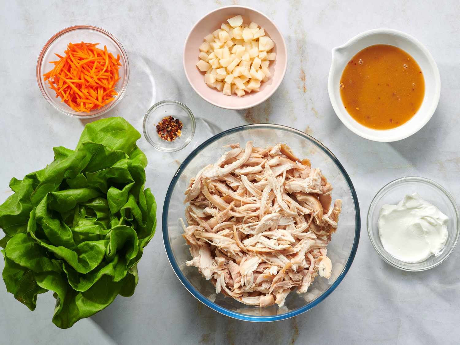 Butter lettuce, ground chicken, water chestnuts, hoisin sauce, soy sauce, rice vinegar, garlic, ginger, and green onions arranged on a bright kitchen counter