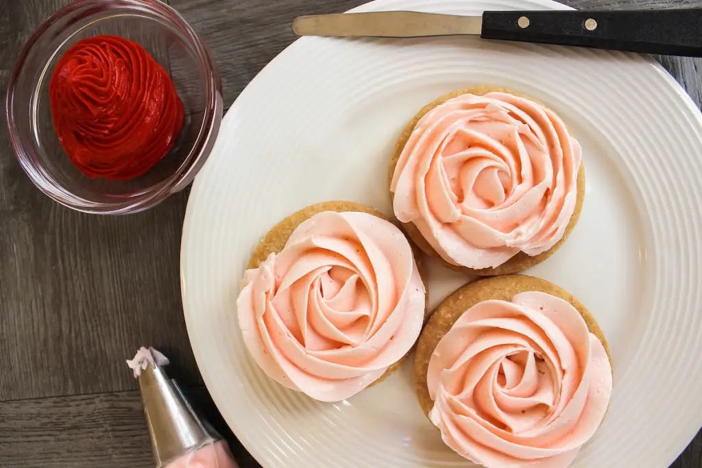 Buttercream rosettes piped in neat spirals on a lined baking sheet on a bright kitchen counter