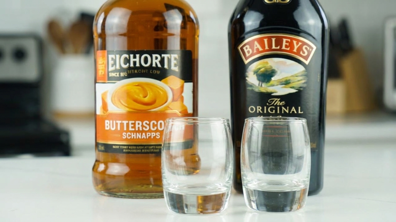 Butterscotch schnapps and Irish cream set on a kitchen counter with two clean shot glasses beside them, ready to pour