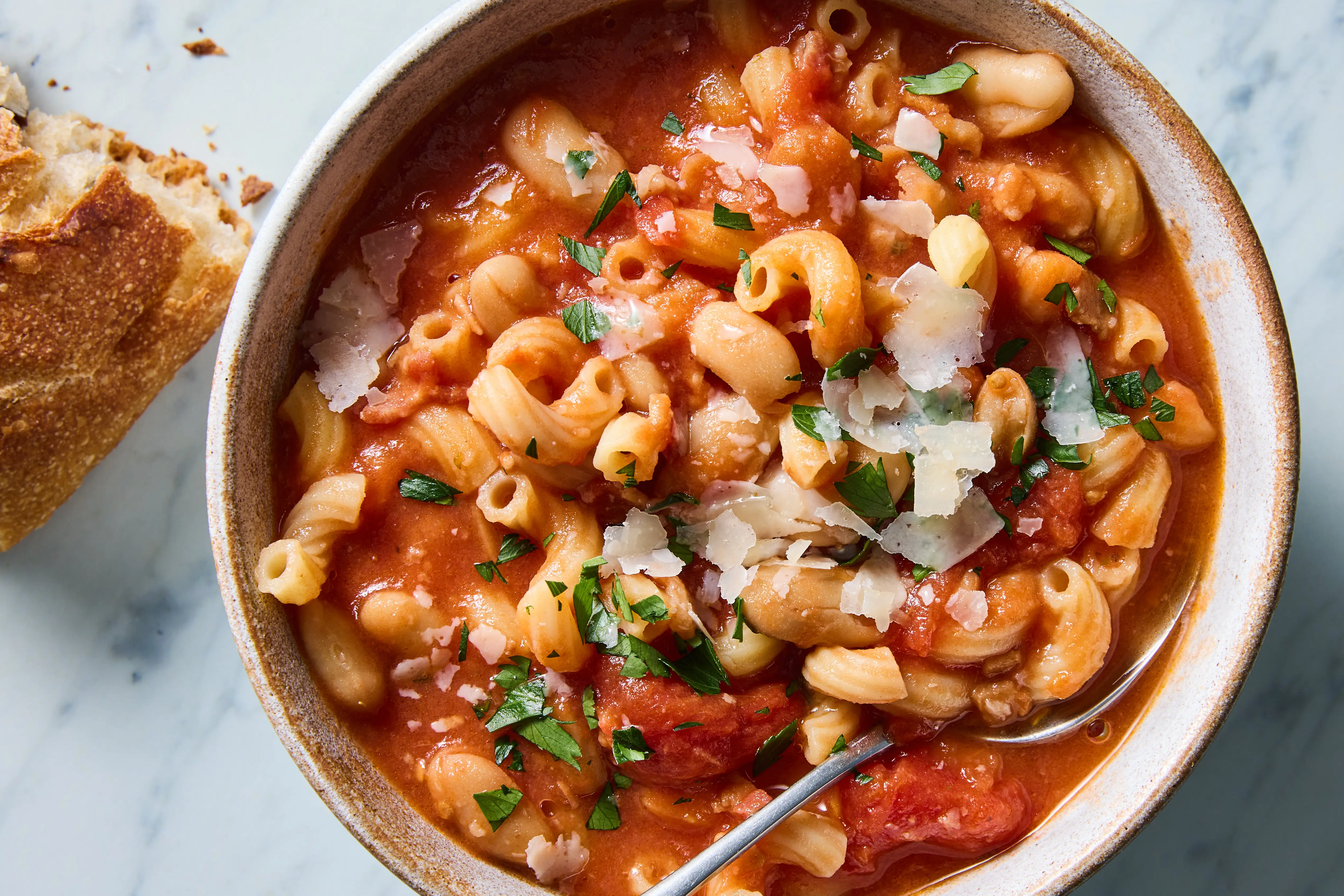Canned cannellini beans, small pasta, canned tomatoes, onion, garlic, carrots, celery, rosemary, olive oil, and Parmesan arranged together for cooking