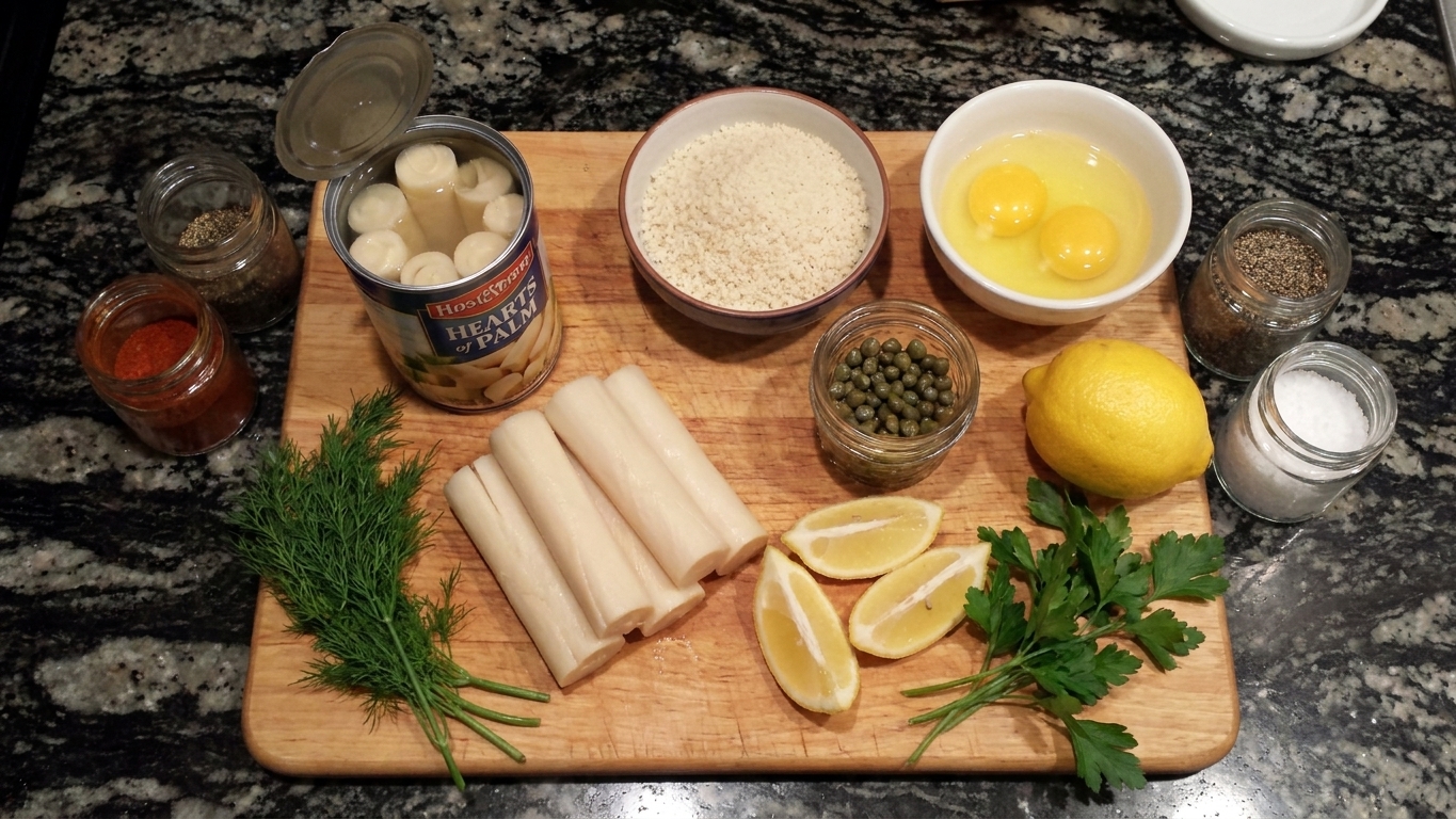 Canned hearts of palm, eggs, breadcrumbs, lemon, capers, herbs, and spices arranged on a light stone kitchen counter with a cutting board