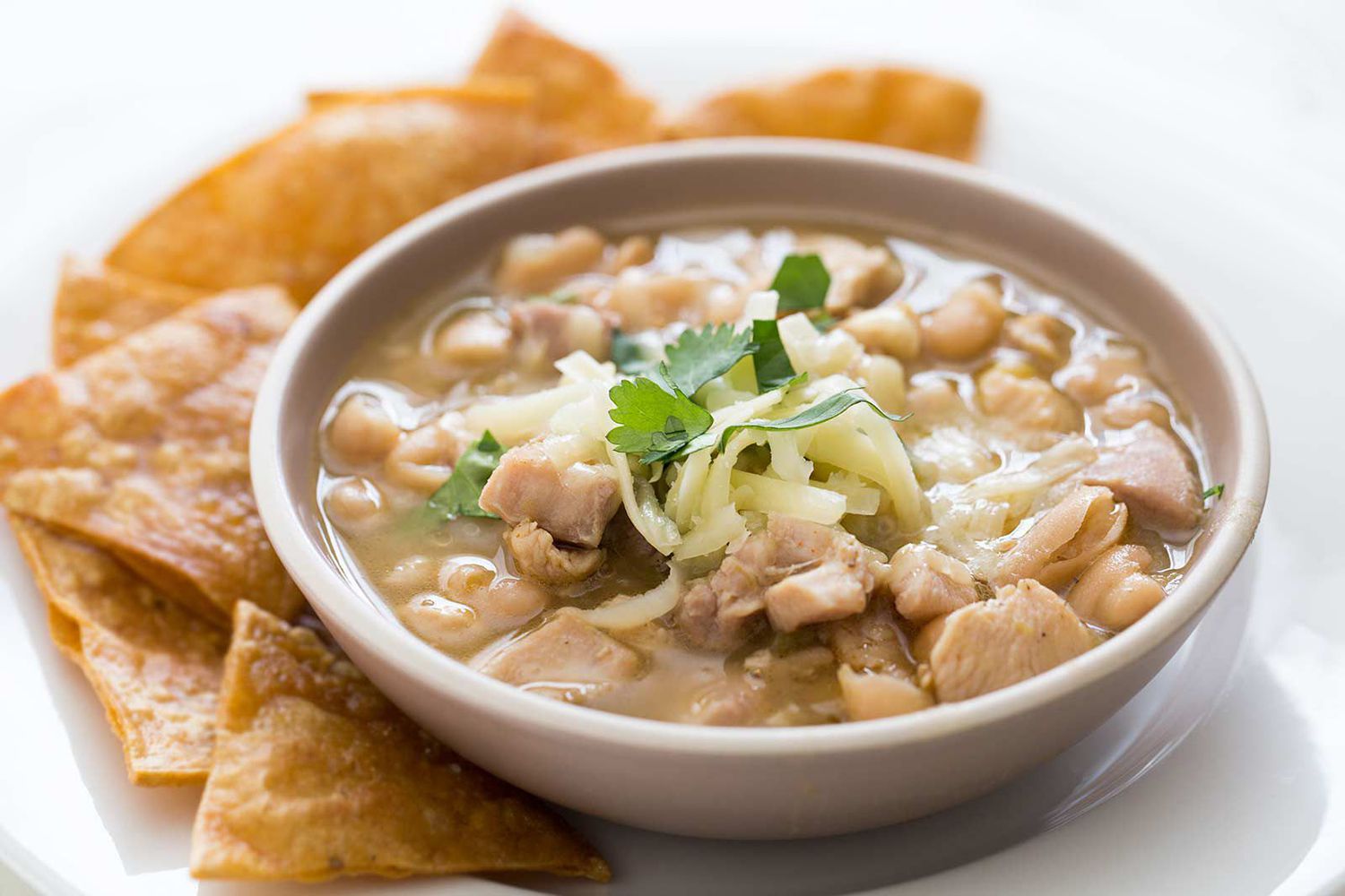 Canned white beans, chicken broth, diced green chiles, onion, garlic, cumin, chili powder, cream cheese, lime, and cilantro arranged on a bright kitchen counter