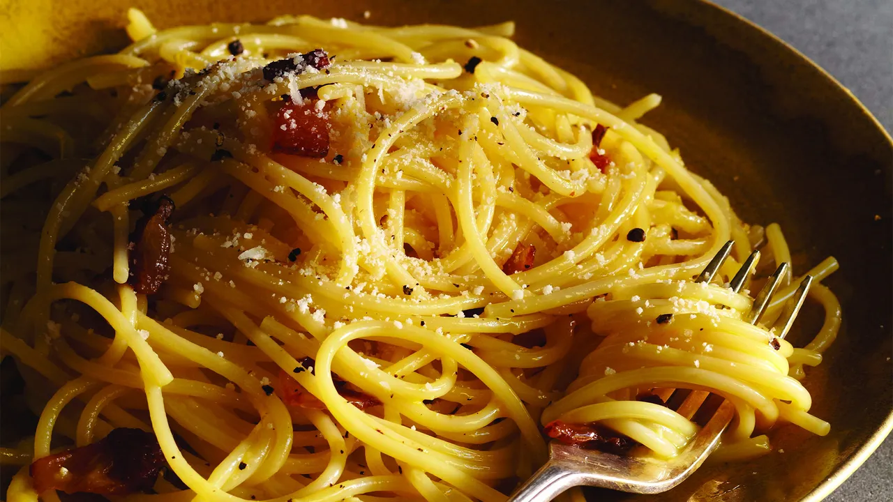 Carbonara ingredients arranged together: spaghetti, guanciale, eggs, Pecorino Romano, Parmesan, and a pepper grinder